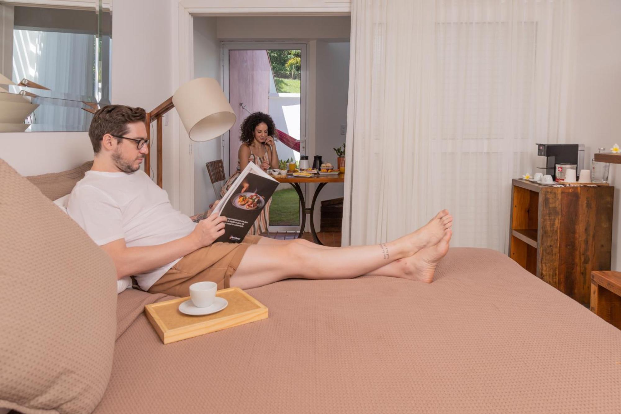 Hotel Boutique Frangipani Brotas Exterior photo A man reading a book while a woman cooks